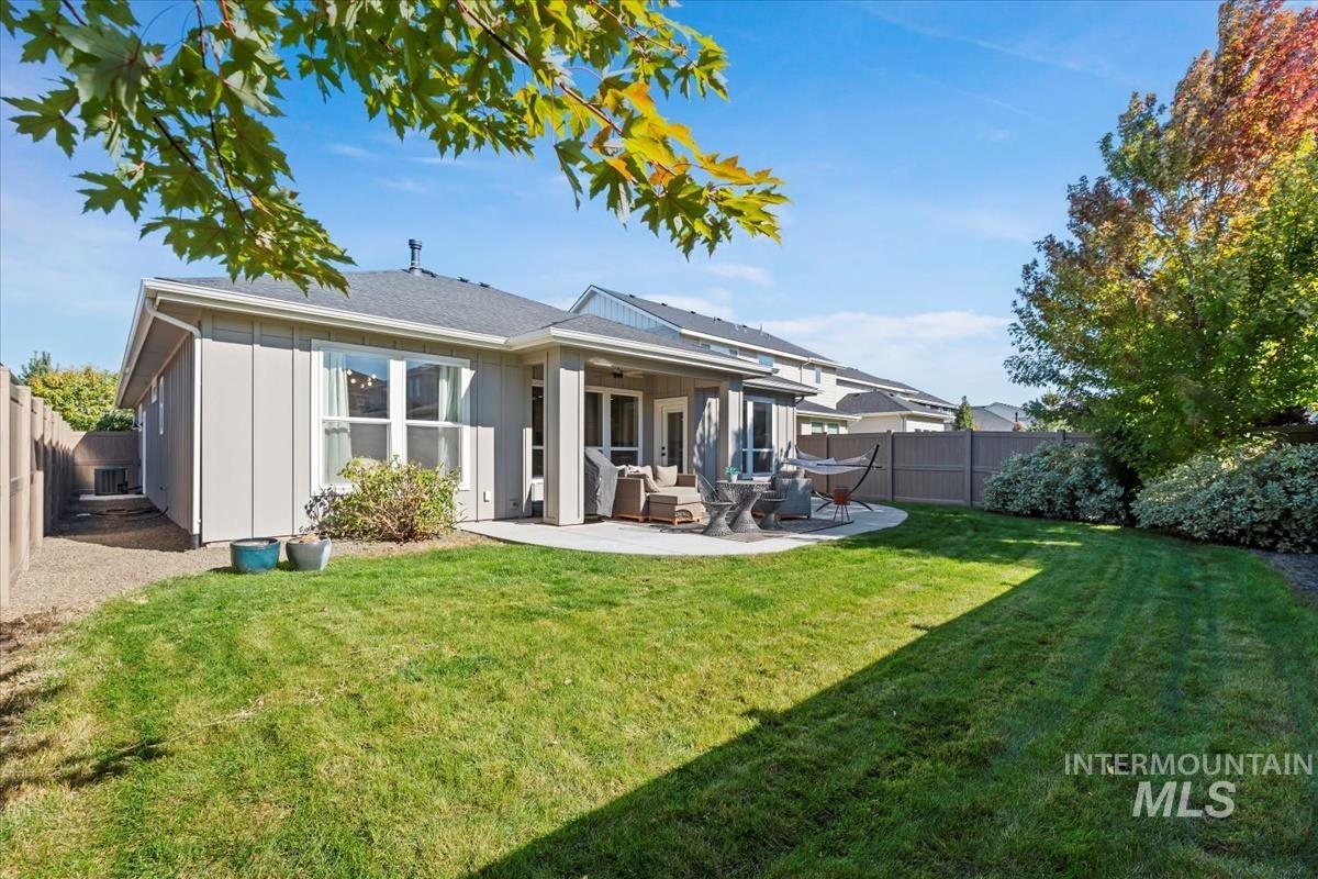 Rear view of property with a fenced backyard, a patio, board and batten siding, a ceiling fan, and an outdoor hangout area