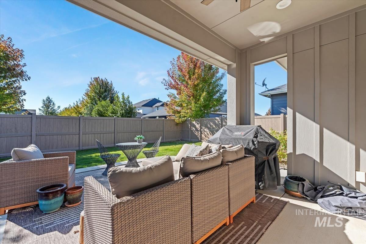 Fenced backyard featuring a patio area, an outdoor living space, grilling area, and a ceiling fan