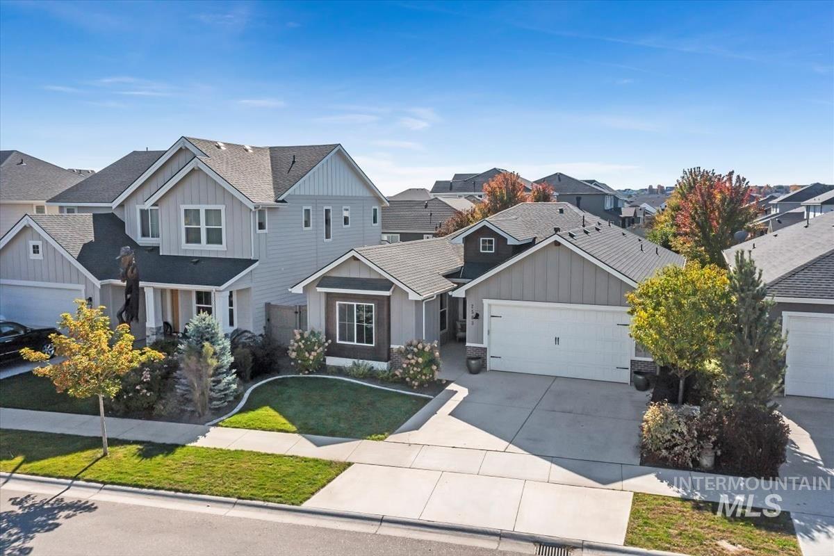Craftsman-style house with board and batten siding, concrete driveway, a front yard, a garage, and a residential view