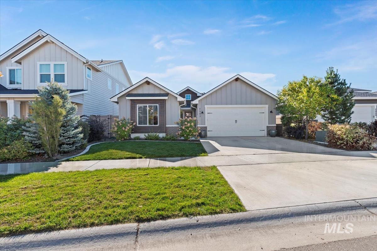Craftsman house featuring board and batten siding, driveway, a front lawn, and an attached garage
