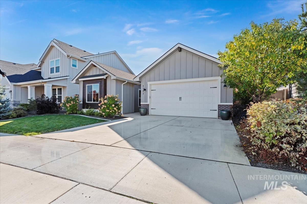 Craftsman inspired home featuring board and batten siding, concrete driveway, brick siding, an attached garage, and a front yard
