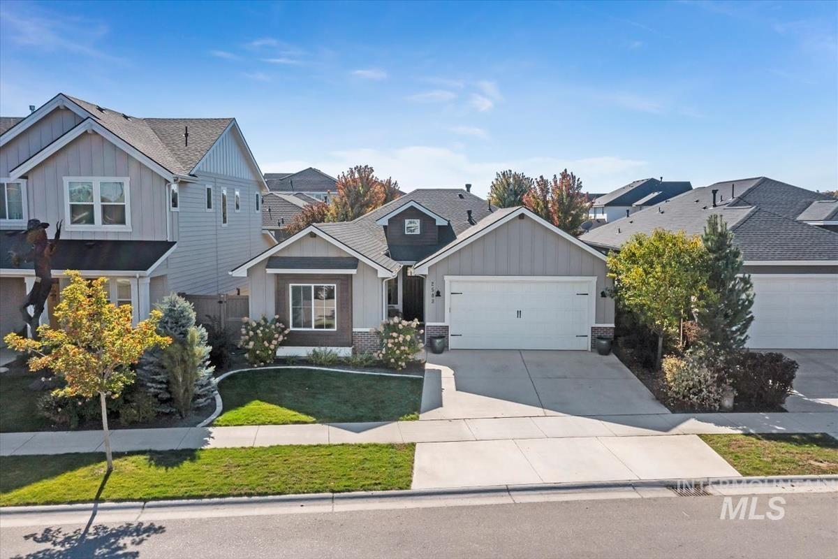 Craftsman inspired home with board and batten siding, driveway, an attached garage, a front yard, and a residential view