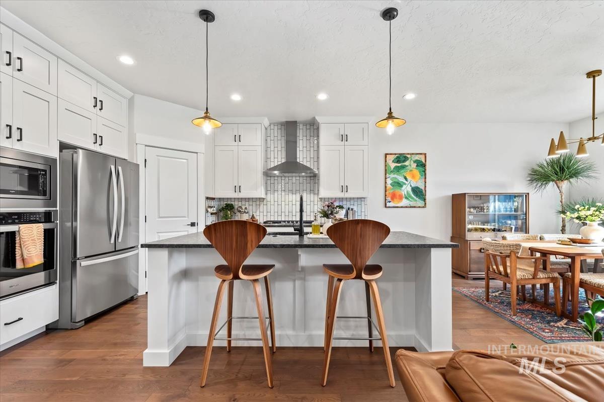 Kitchen with white cabinets, pendant lighting, stainless steel appliances, open floor plan, and recessed lighting