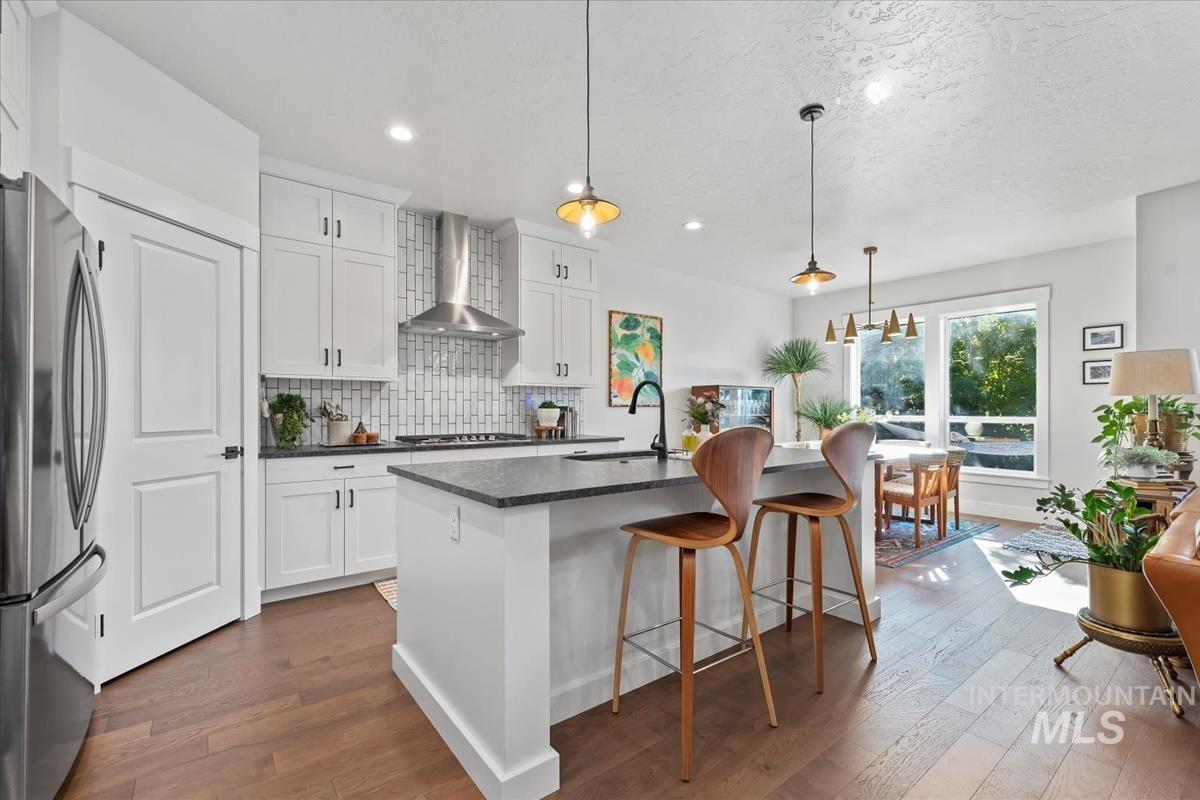 Kitchen with tasteful backsplash, freestanding refrigerator, dark wood-type flooring, a breakfast bar, and recessed lighting