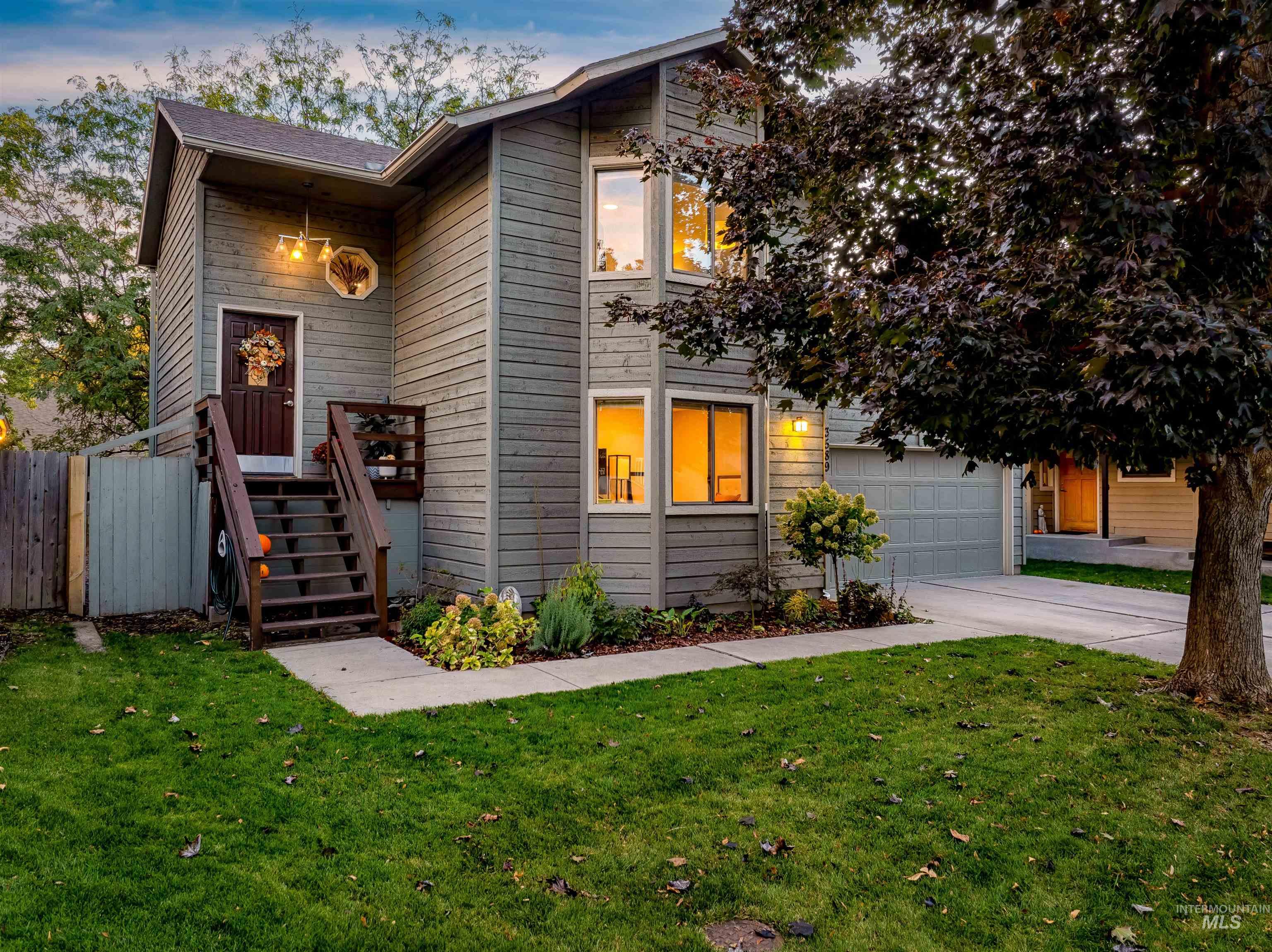 View of front of home with a garage, driveway, and stairs