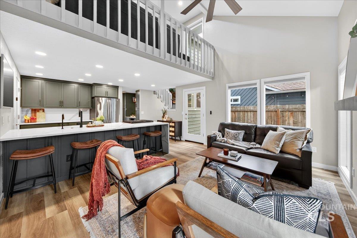 Living area featuring light wood-style floors, a towering ceiling, a ceiling fan, recessed lighting, and stairs