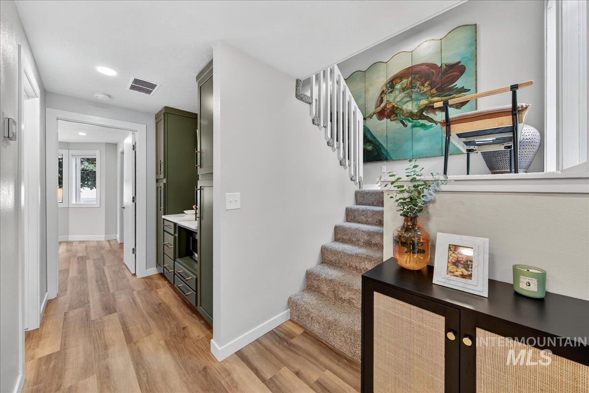 Corridor featuring light wood-type flooring, stairs, and recessed lighting