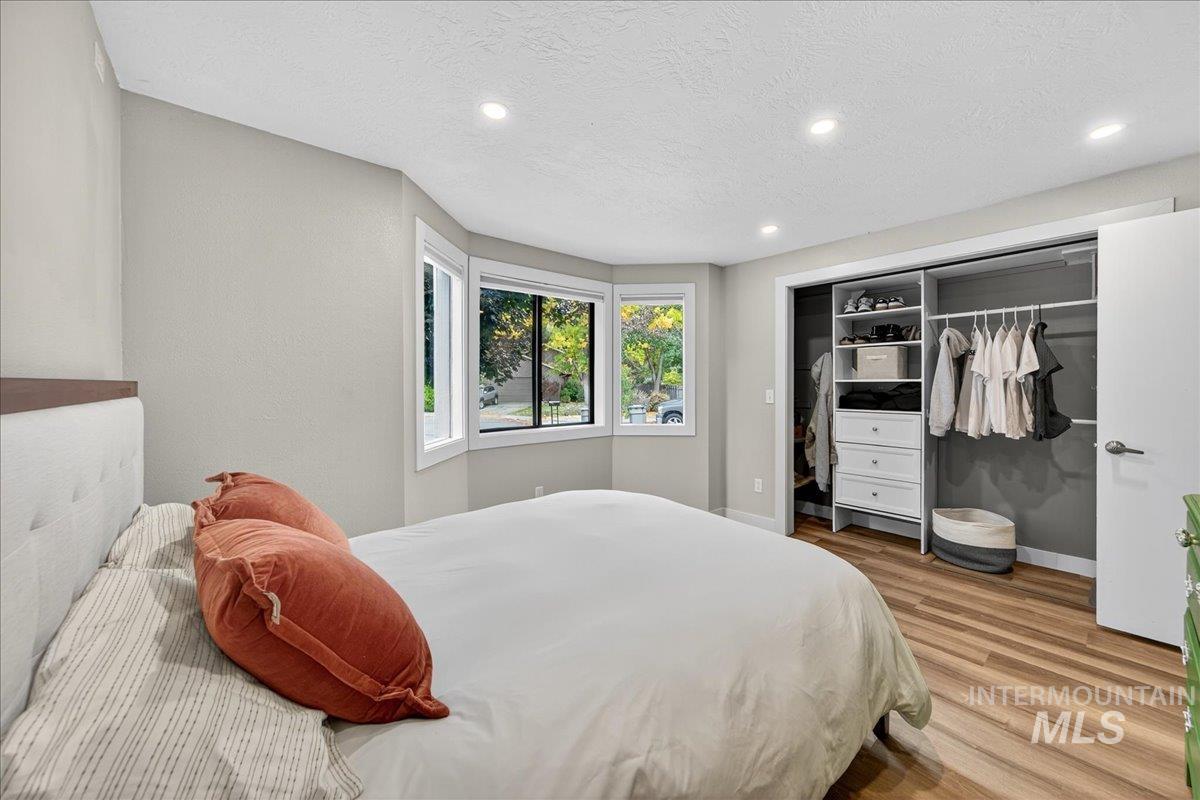 Bedroom featuring a textured ceiling, wood finished floors, recessed lighting, and a closet