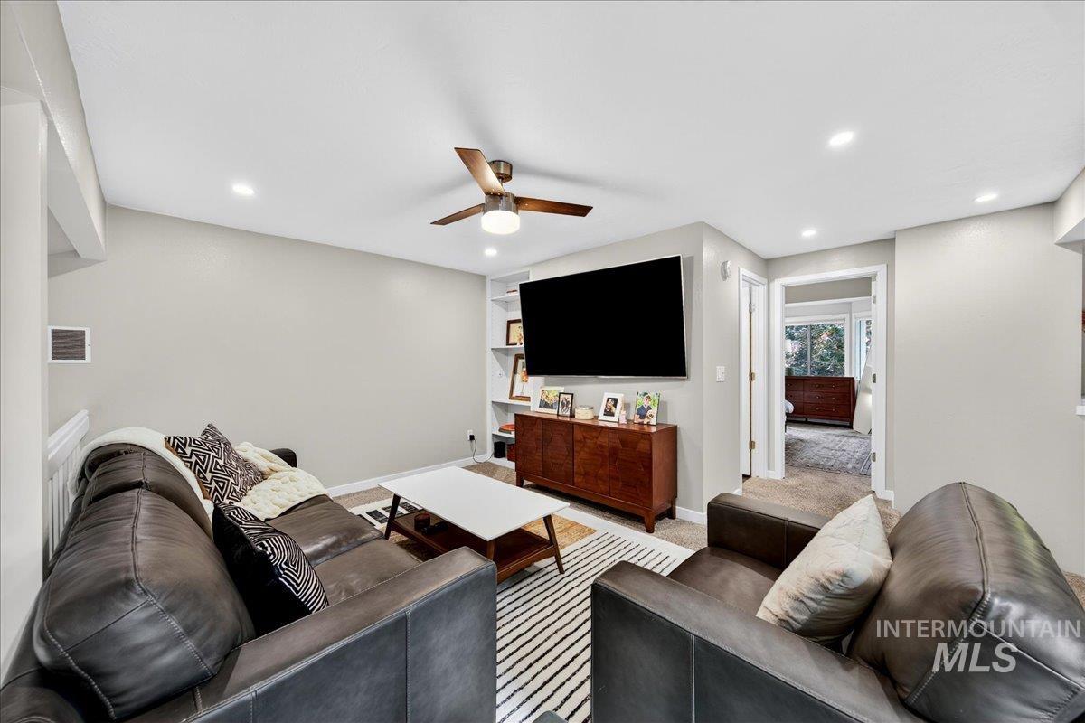 Carpeted living room featuring a ceiling fan and recessed lighting