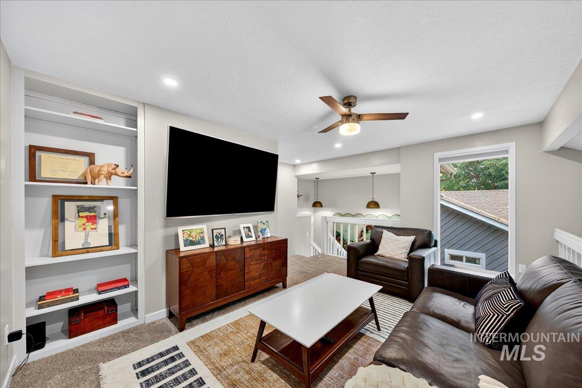 Living area featuring light carpet, built in features, a ceiling fan, recessed lighting, and a textured ceiling