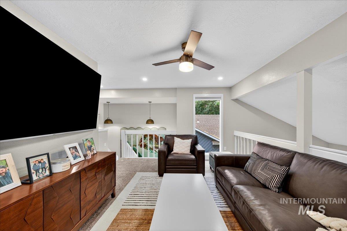 Living room featuring light colored carpet, a textured ceiling, a ceiling fan, and recessed lighting