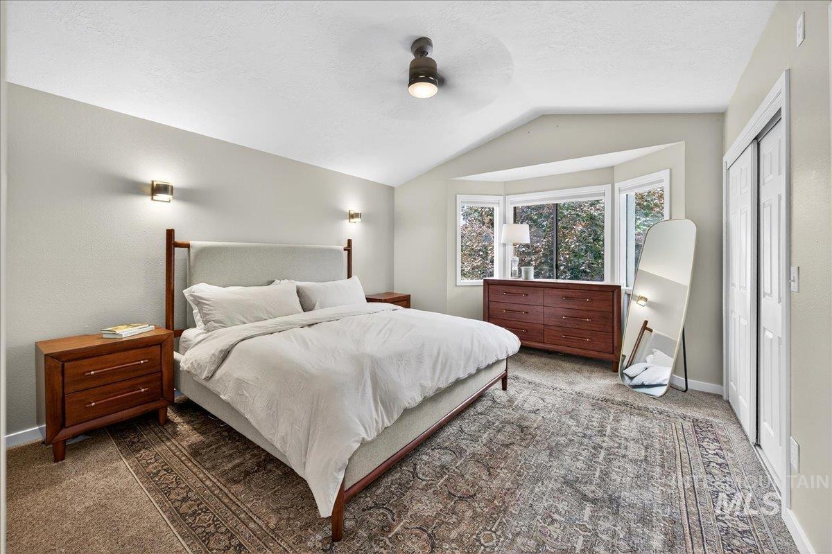 Bedroom featuring lofted ceiling, carpet flooring, a closet, ceiling fan, and a textured ceiling