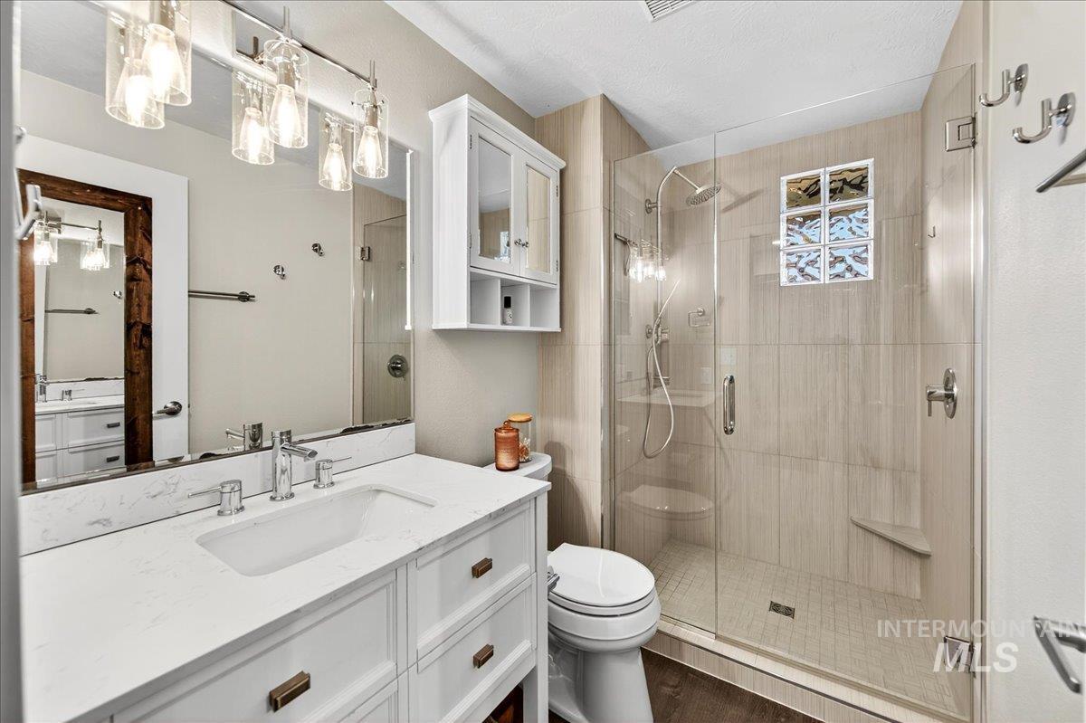 Bathroom with vanity, a shower stall, and dark wood-type flooring