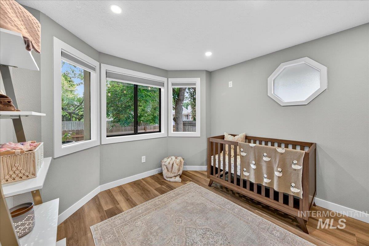 Bedroom featuring a nursery area, wood finished floors, and recessed lighting