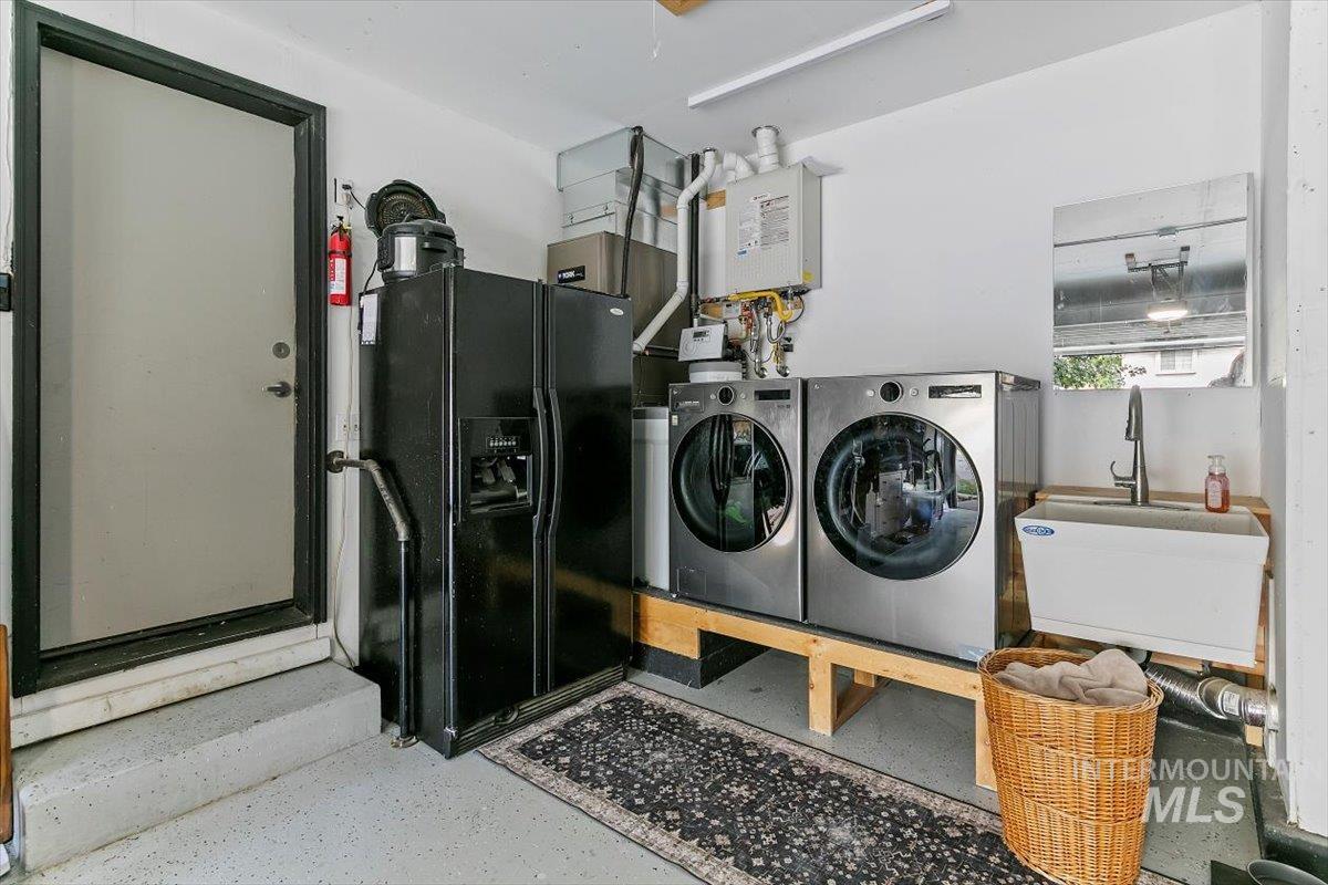 Laundry area with washing machine and clothes dryer, speckle patterned floor, and water heater