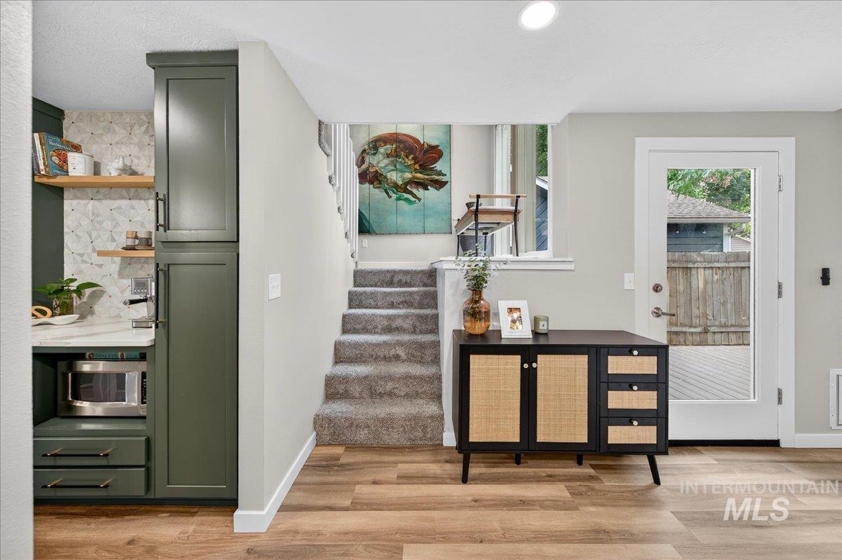 Doorway to outside with wood finished floors, stairway, and recessed lighting