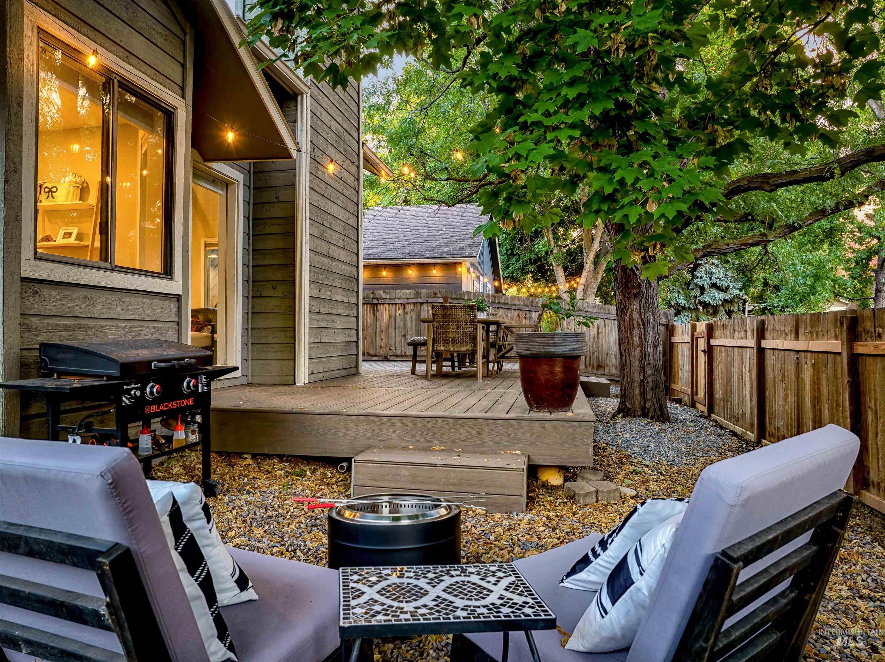 Wooden terrace featuring a fenced backyard, grilling area, and outdoor dining space
