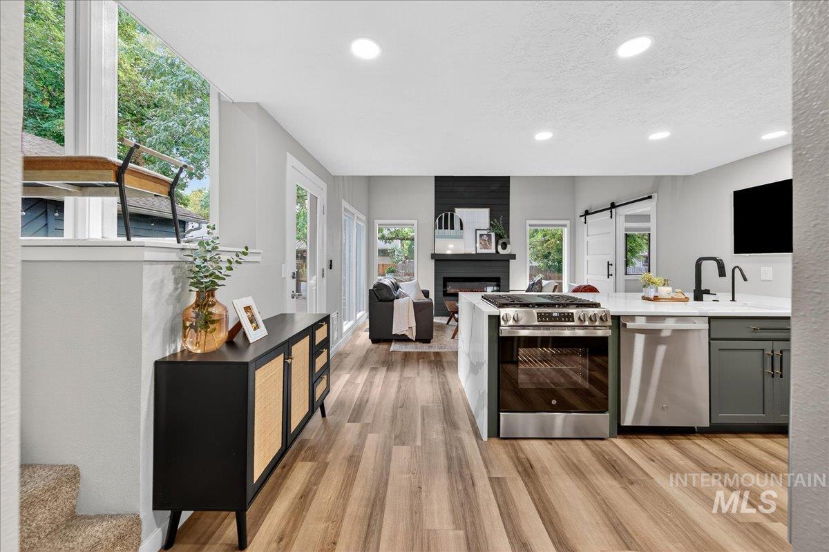 Kitchen with a barn door, stainless steel appliances, a peninsula, recessed lighting, and light wood-style floors