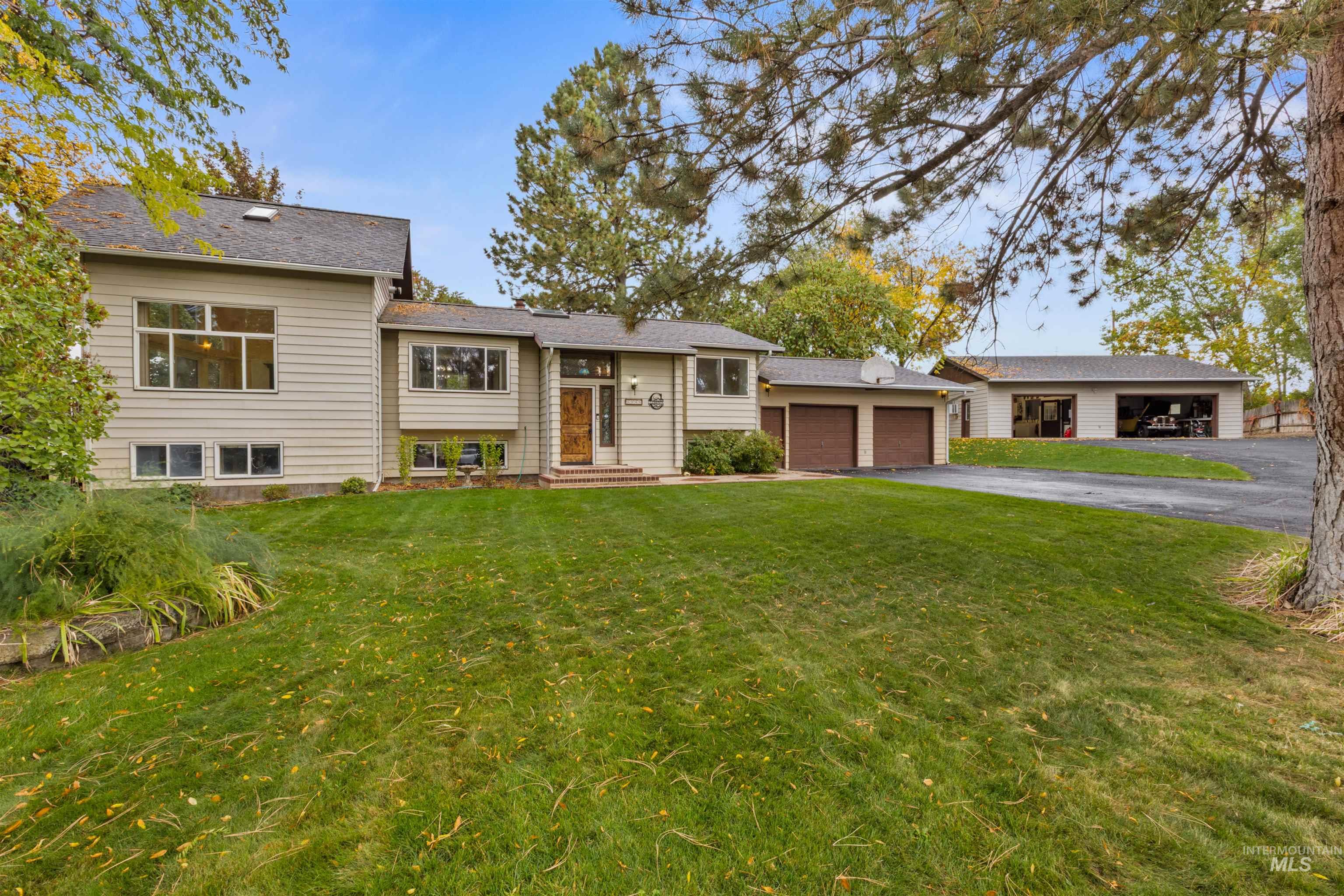 Raised ranch with a front yard, asphalt driveway, and a garage