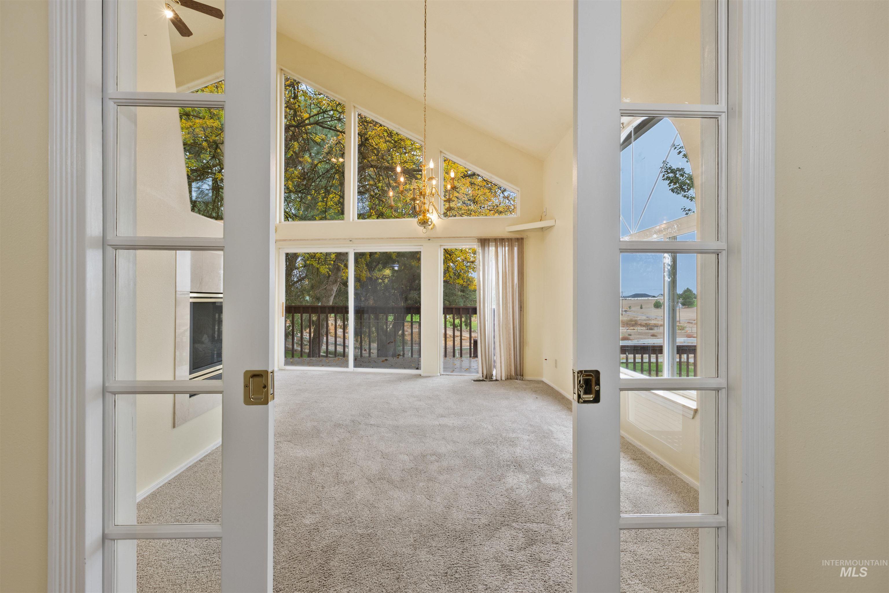 Unfurnished living room with carpet flooring, high vaulted ceiling, and ceiling fan