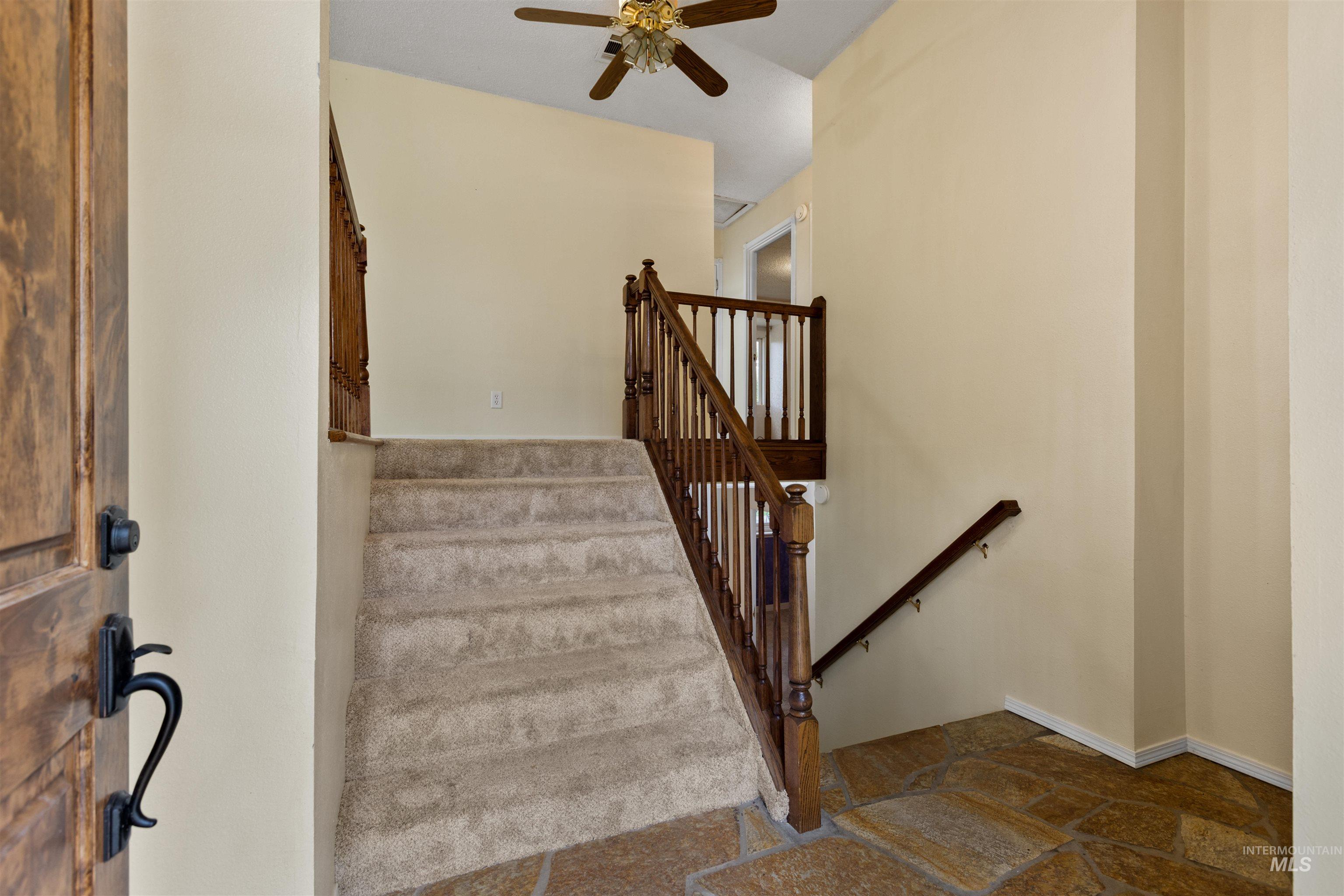 Staircase featuring stone tile flooring and a ceiling fan