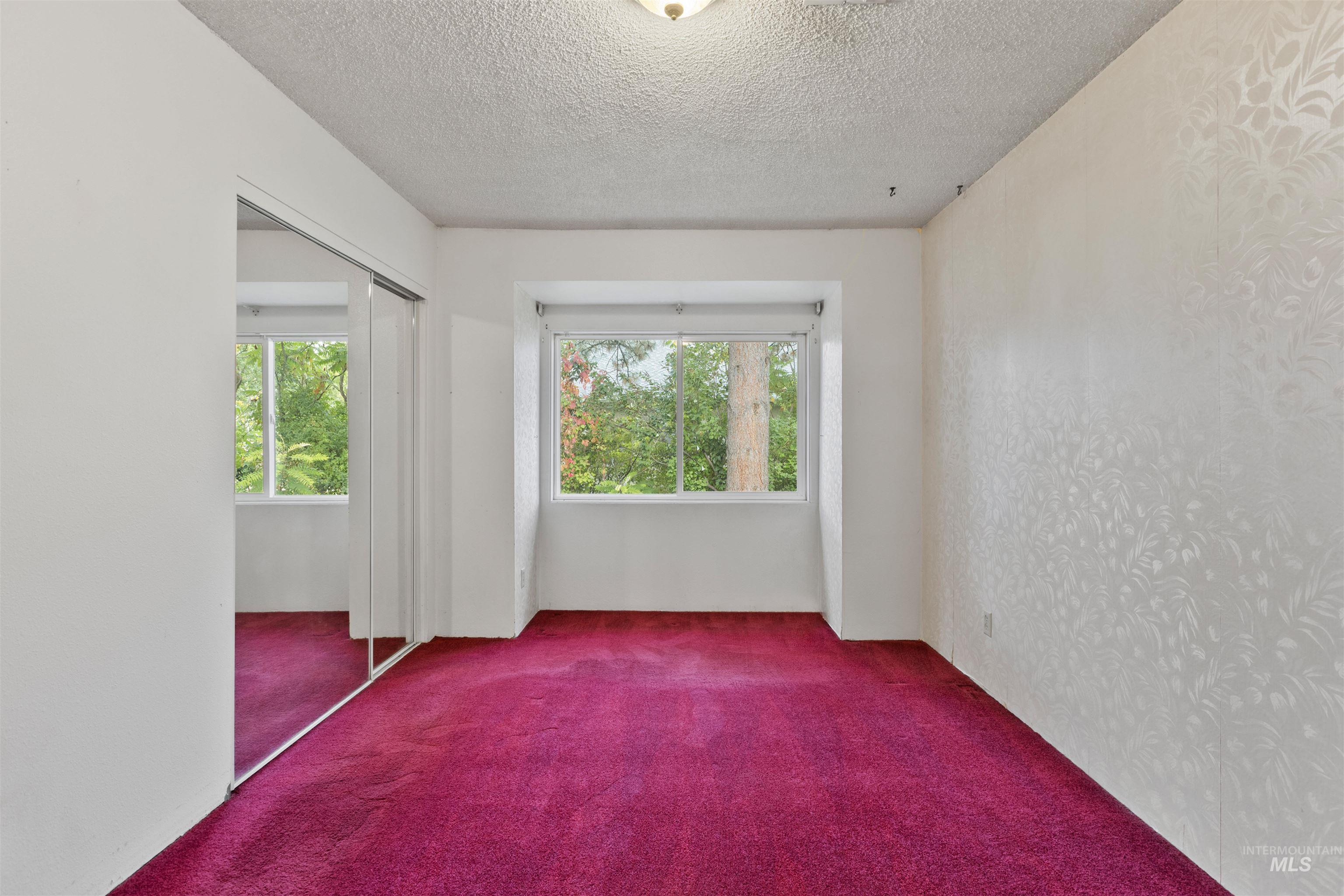 Empty room with carpet flooring, healthy amount of natural light, and a textured ceiling