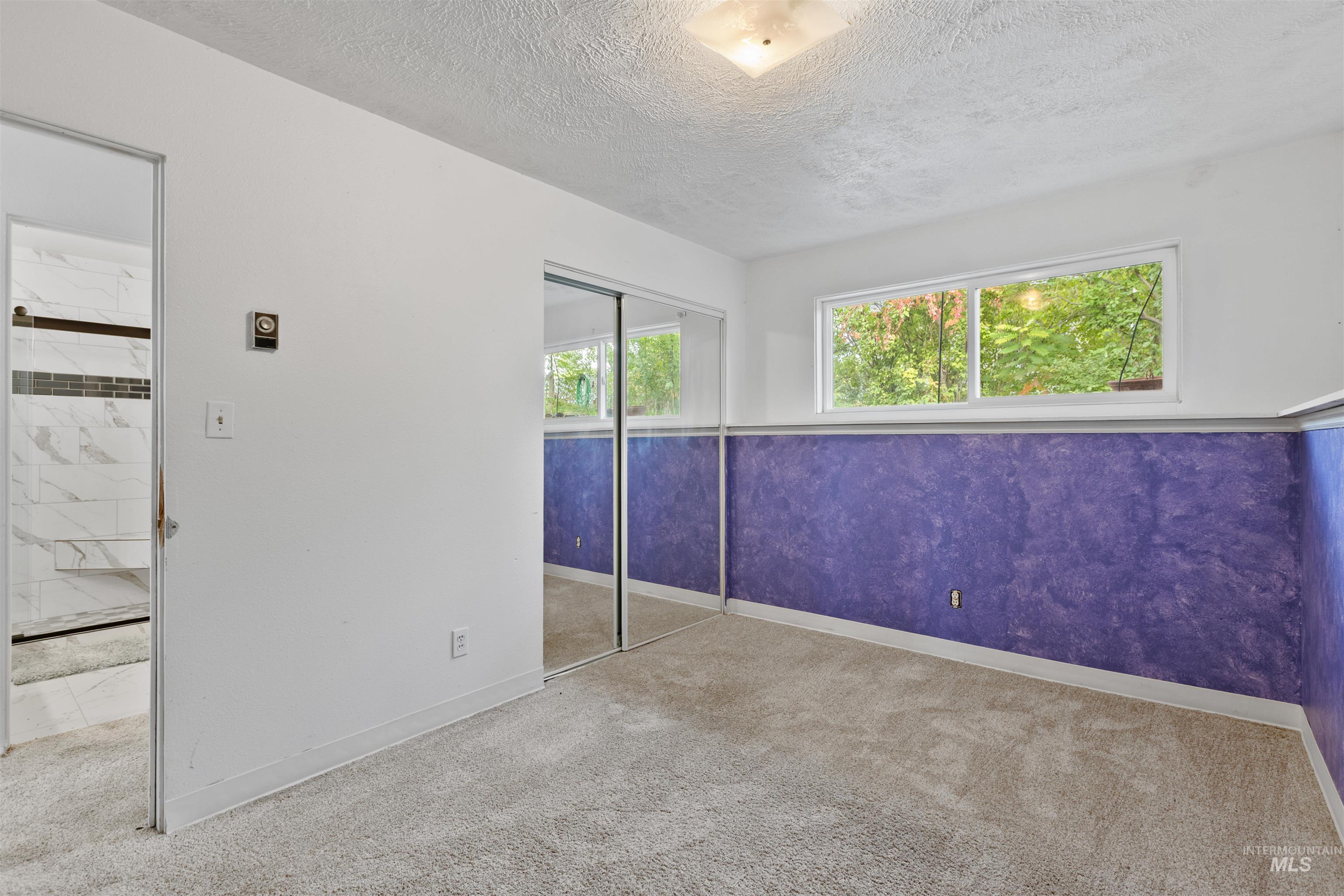 Unfurnished bedroom with carpet flooring, a textured ceiling, and a closet