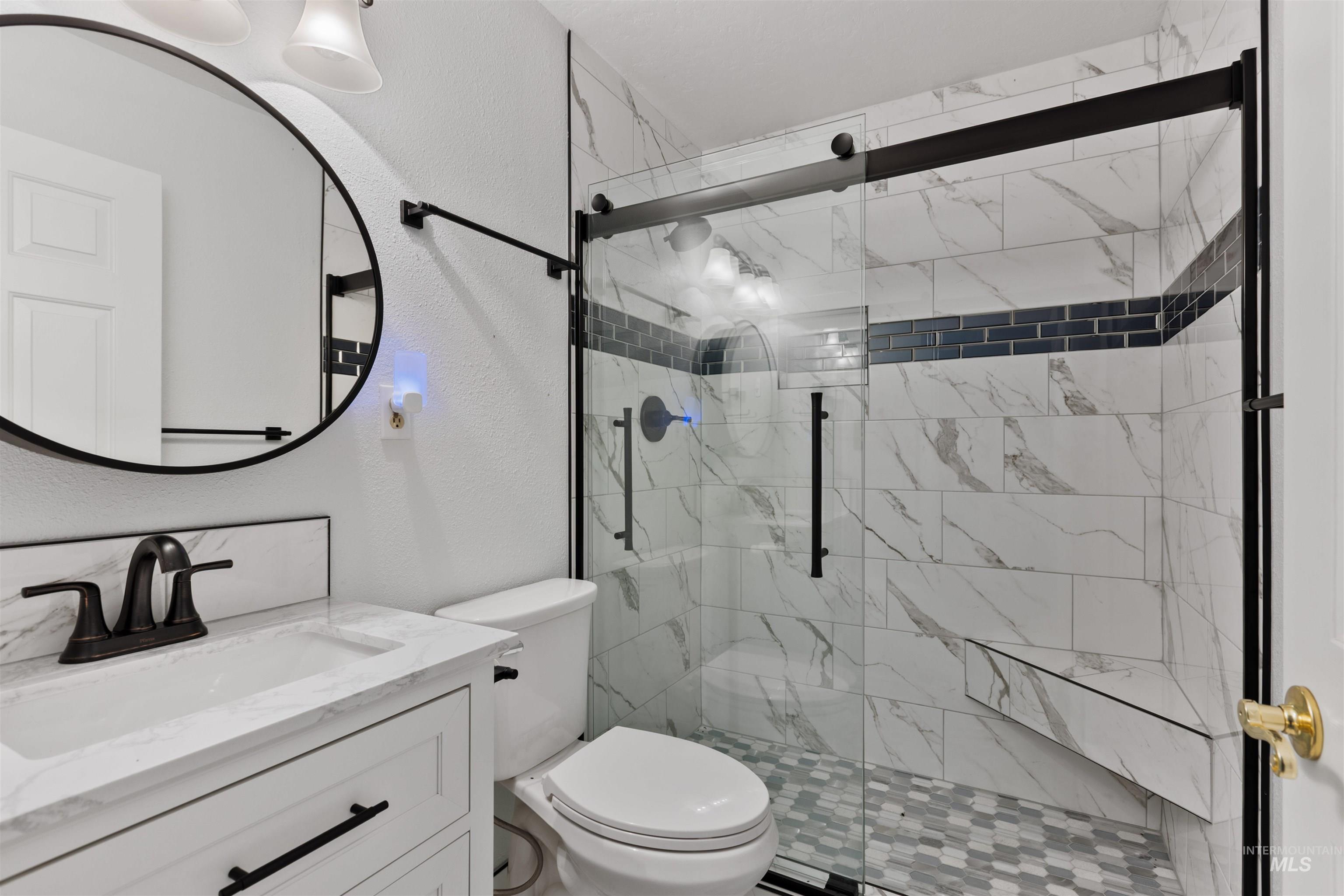 Bathroom featuring a textured wall, a shower stall, and vanity
