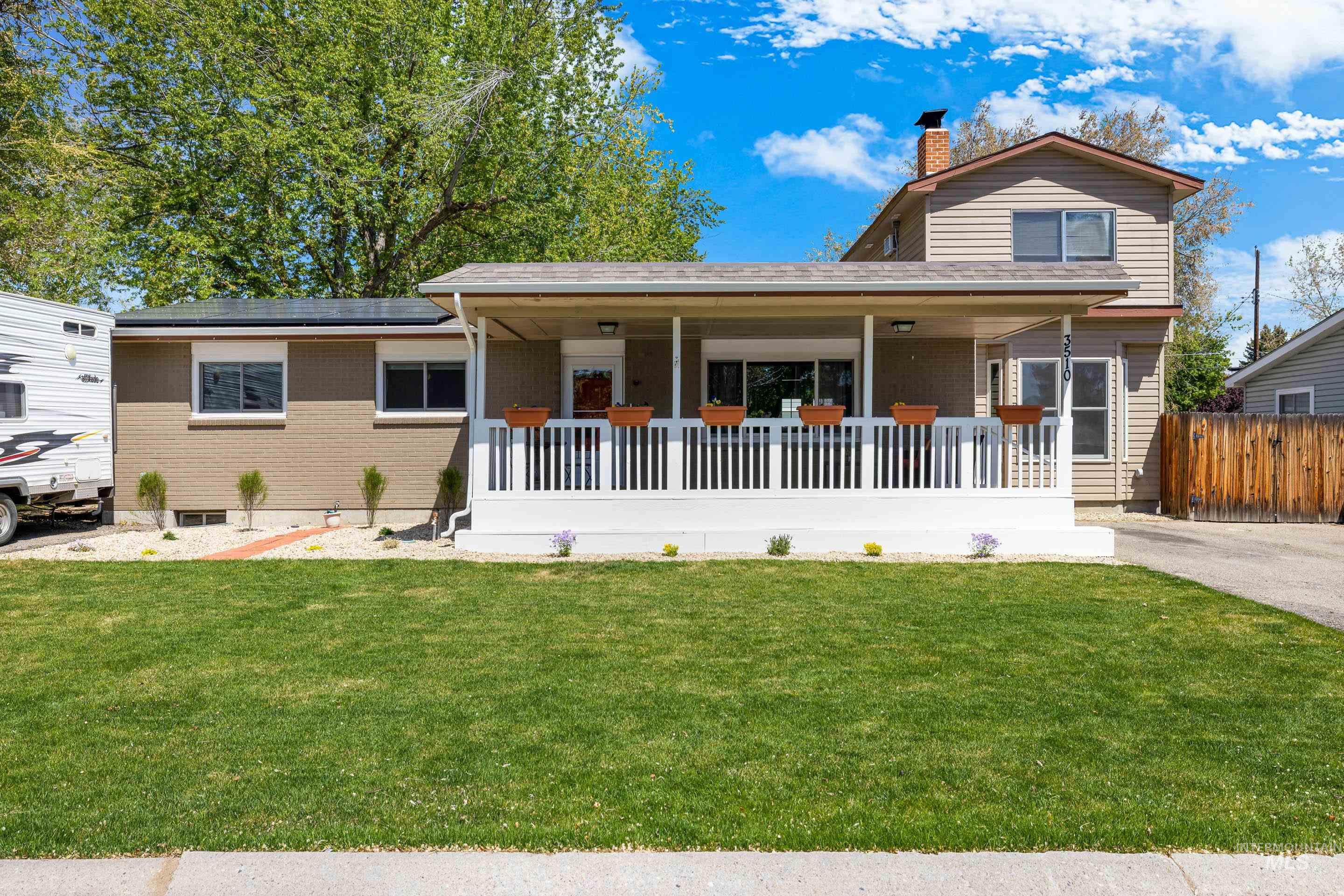 View of front of property with covered porch, a front yard, a chimney, and brick siding