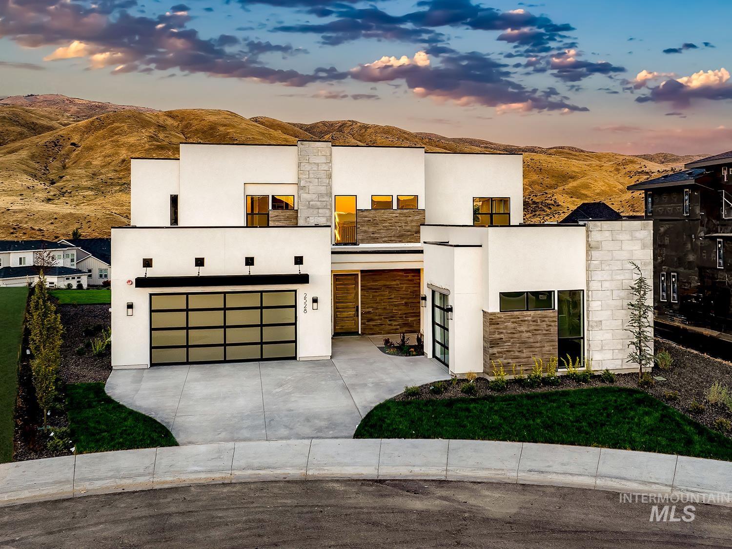 Modern home featuring stone siding, stucco siding, concrete driveway, a mountain view, and a garage