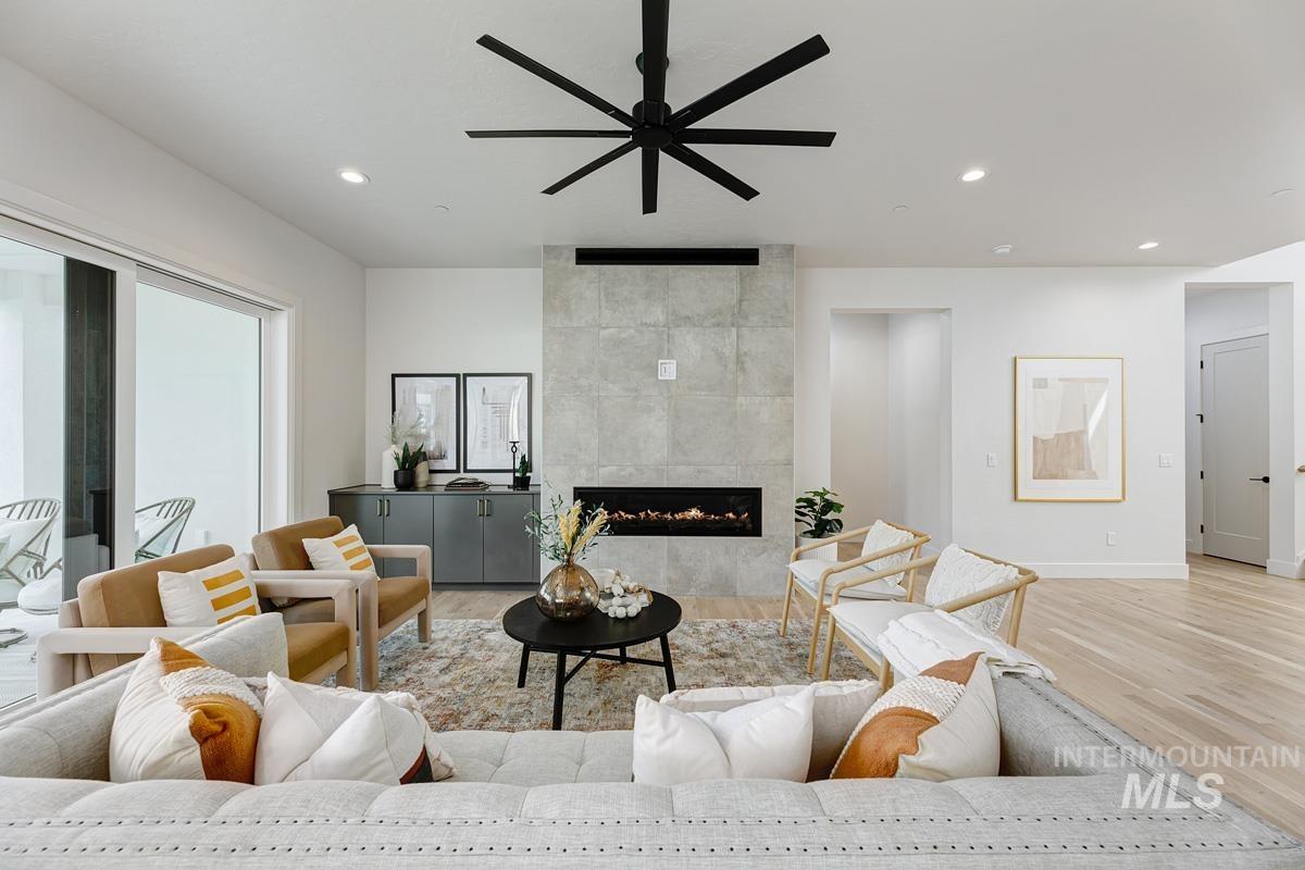 Living room featuring a tiled fireplace, light wood finished floors, recessed lighting, and ceiling fan