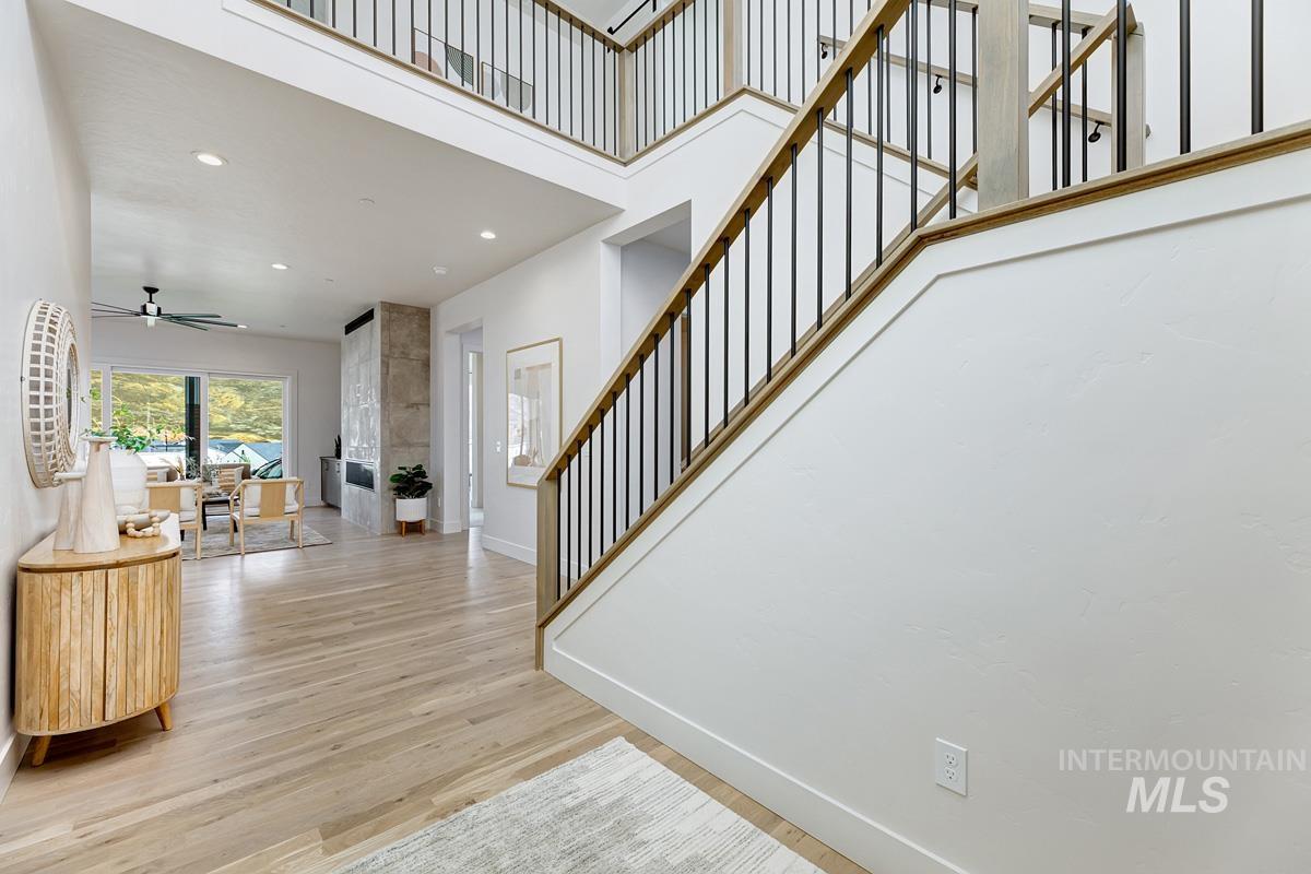 Entrance foyer featuring recessed lighting, a ceiling fan, light wood-style floors, stairway, and a towering ceiling