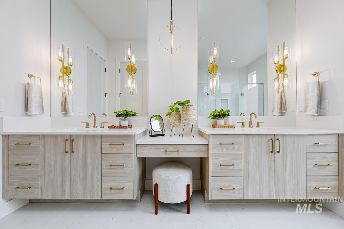 Full bath with two vanities, a stall shower, and light marble finish flooring
