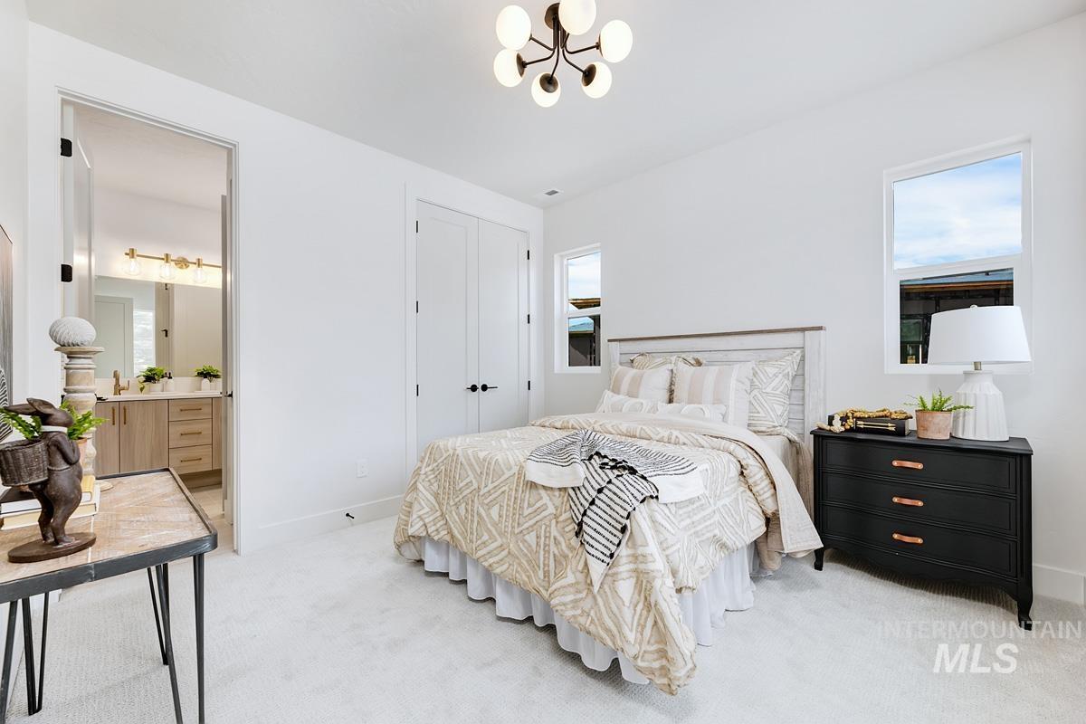 Bedroom with light colored carpet, a chandelier, ensuite bathroom, and a closet