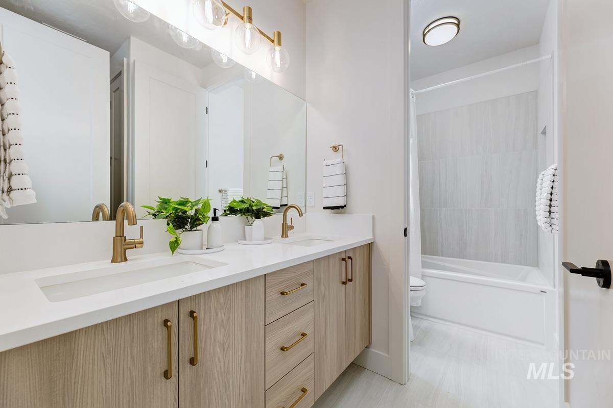 Full bathroom with double vanity and shower / washtub combination