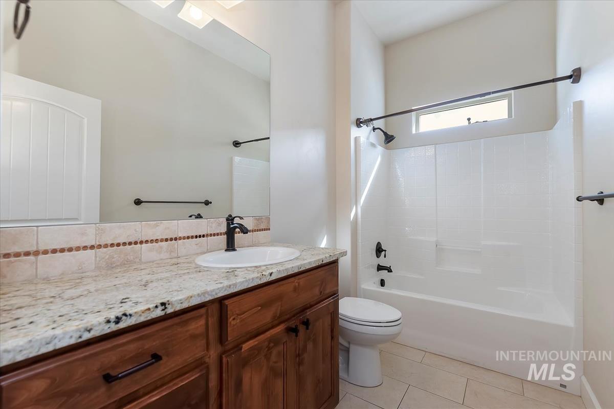 Full bathroom with light tile patterned flooring,  shower combination, vanity, and tasteful backsplash