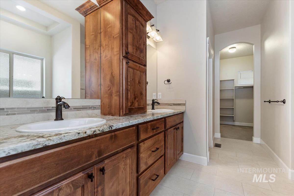 Full bathroom with a spacious closet, double vanity, and light tile patterned flooring