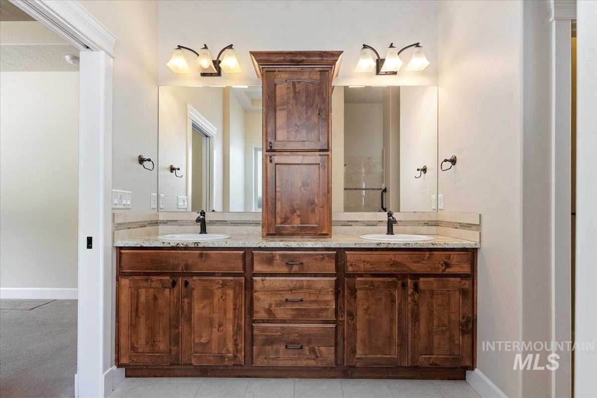 Full bath with double vanity and light tile patterned floors