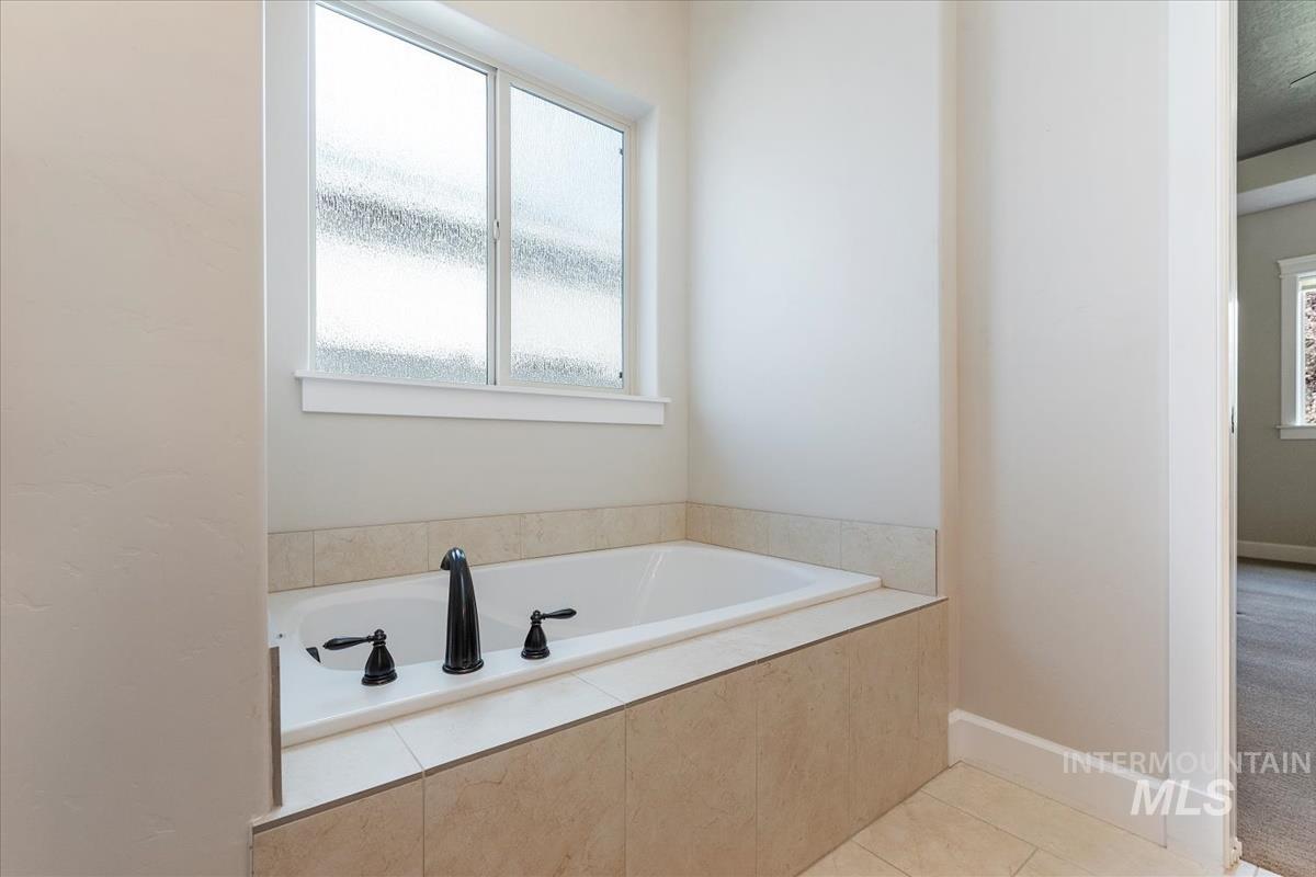 Full bath with a garden tub and light tile patterned floors