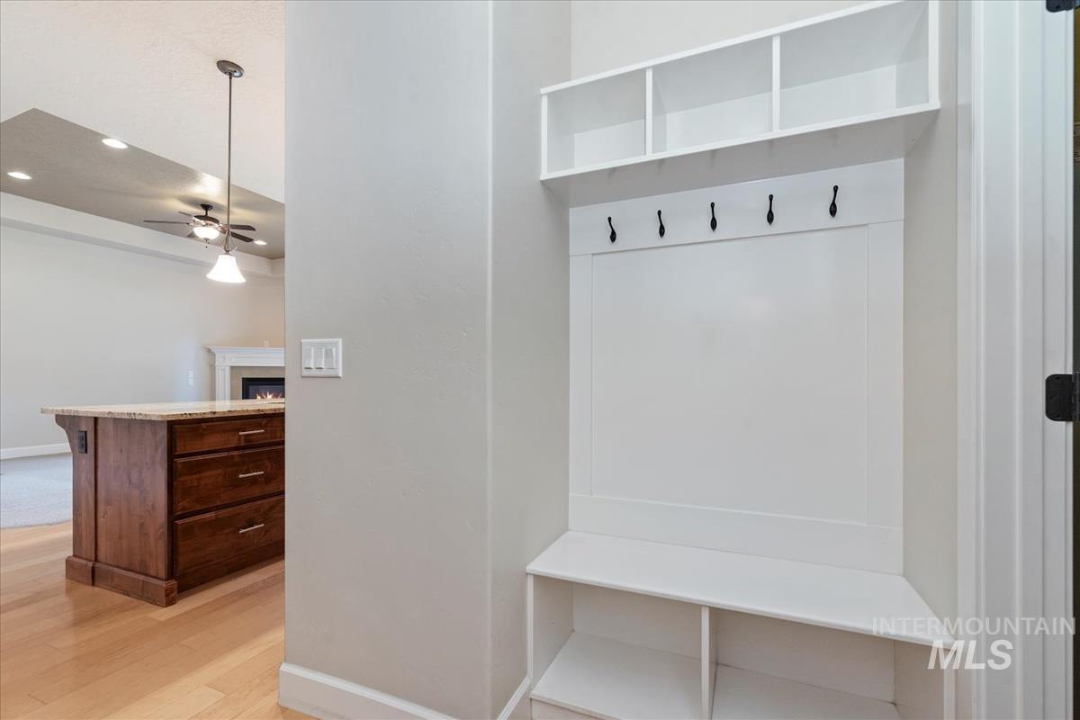 Mudroom featuring light wood-type flooring, a ceiling fan, a warm lit fireplace, and recessed lighting