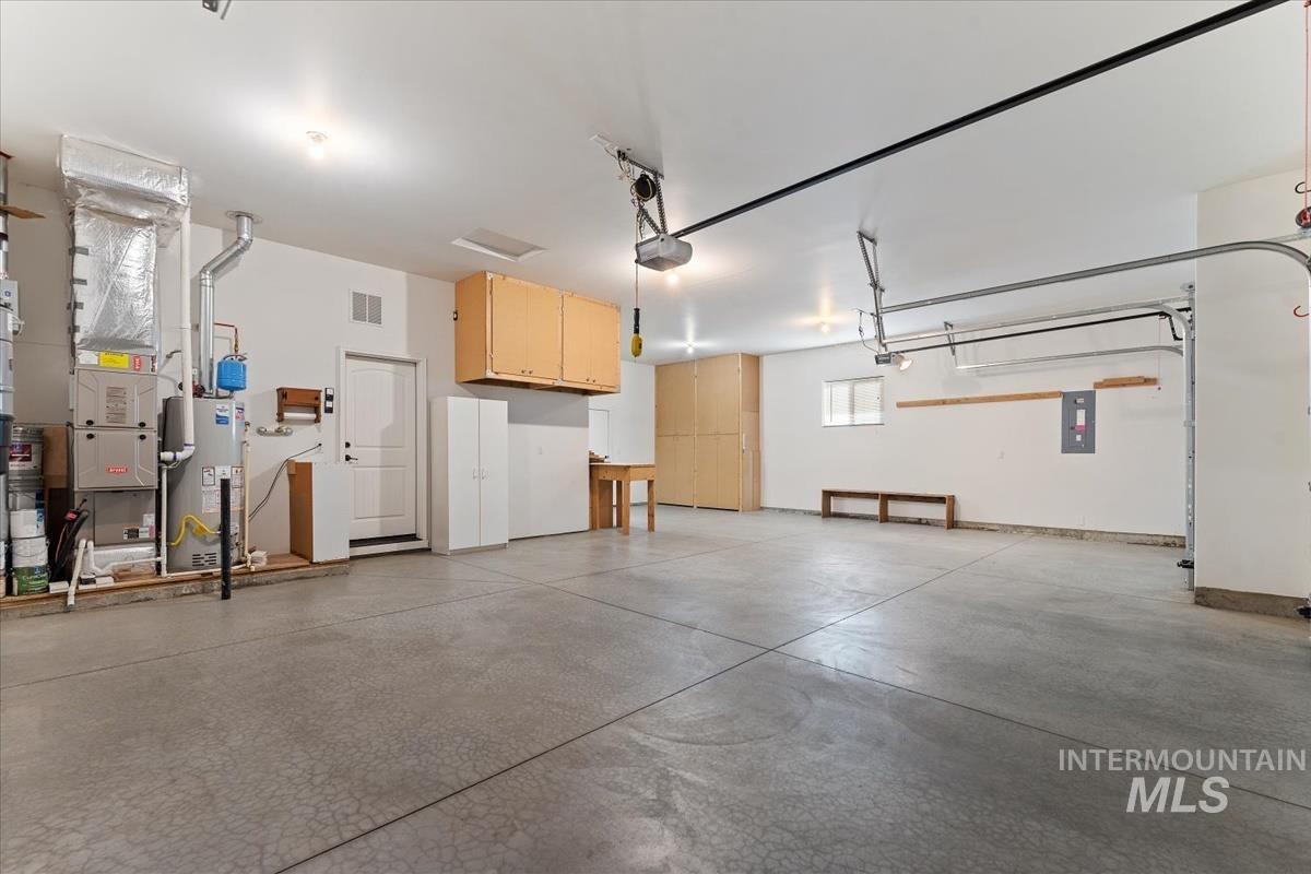Garage with water heater, heating unit, and electric panel