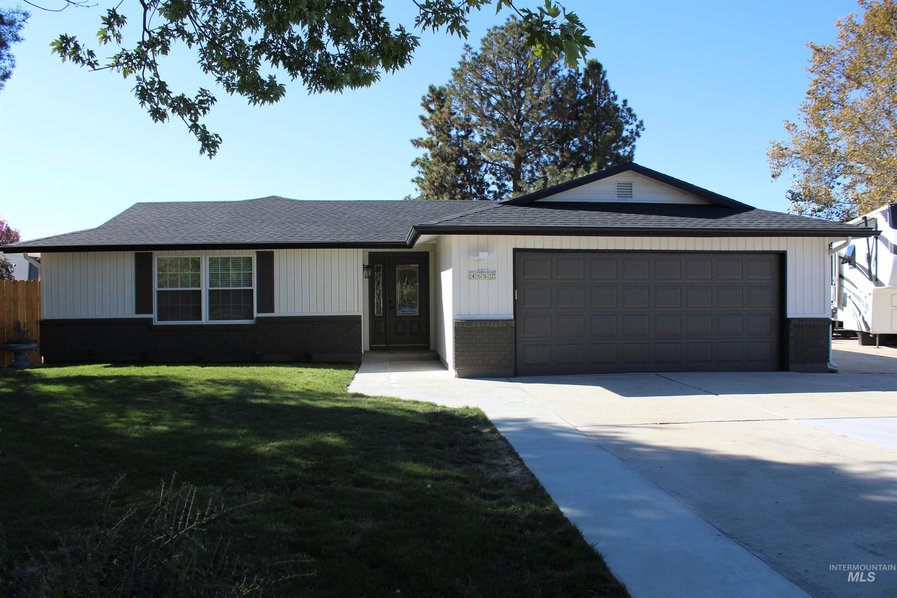 Ranch-style home featuring a front yard, roof with shingles, driveway, a garage, and brick siding