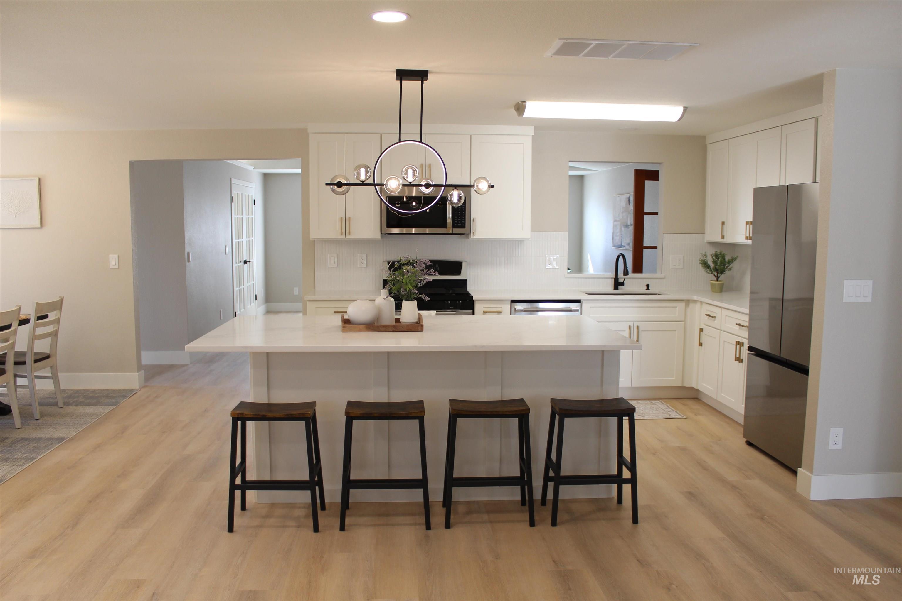 Kitchen featuring appliances with stainless steel finishes, white cabinets, tasteful backsplash, a center island, and recessed lighting