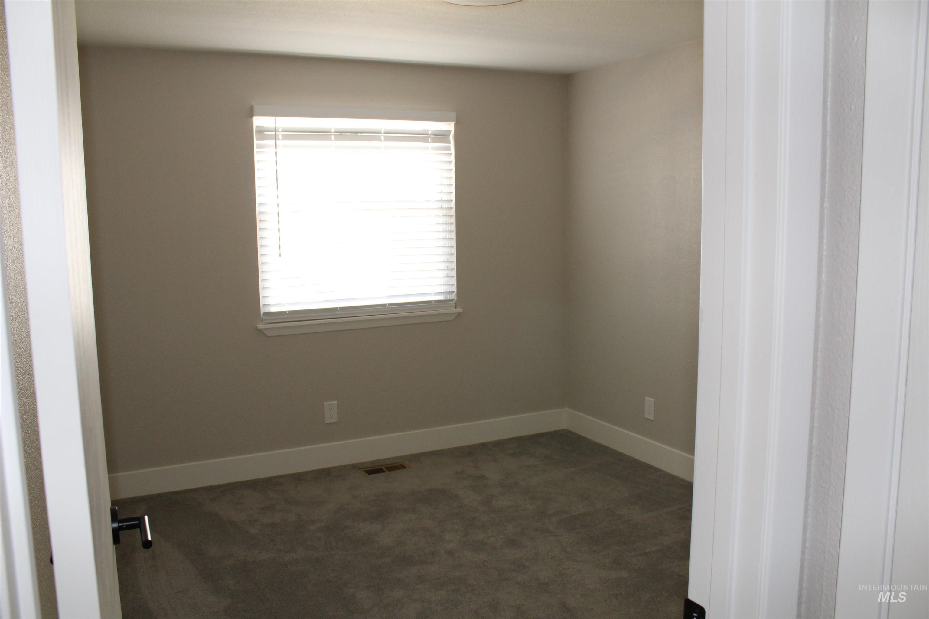 Unfurnished room with dark carpet and baseboards