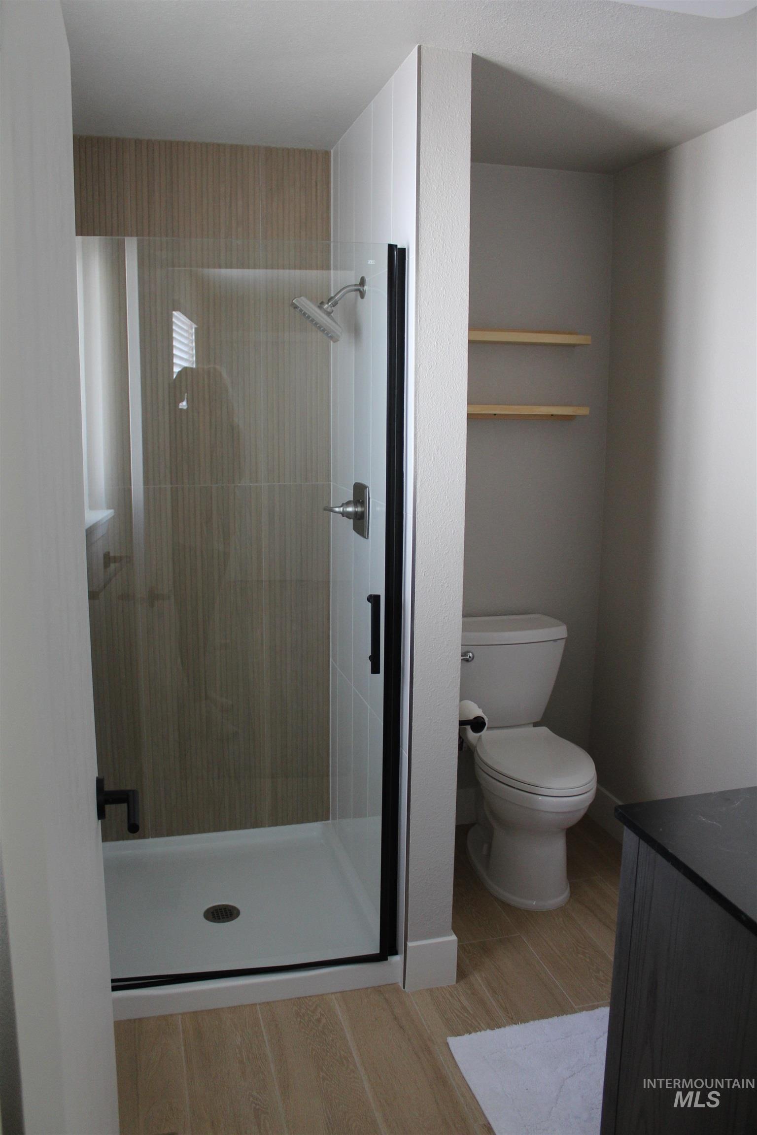 Bathroom featuring a stall shower, light wood finished floors, and vanity