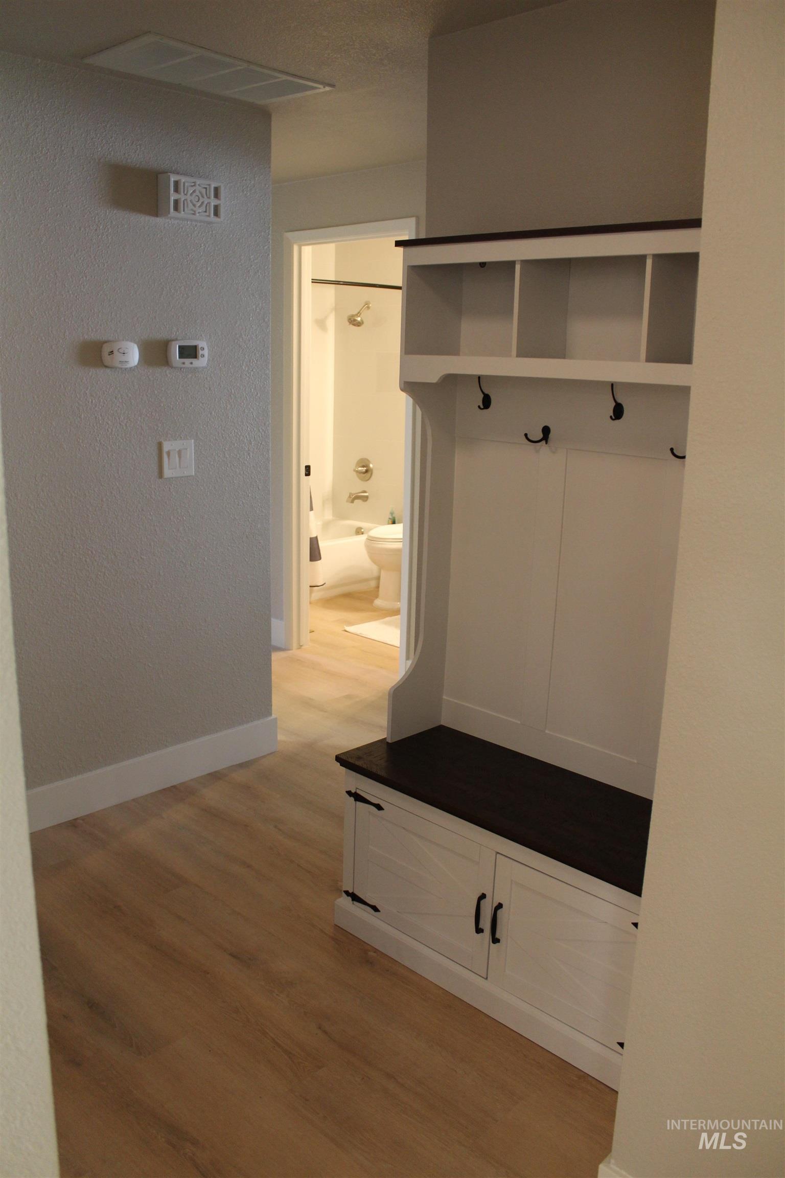 Mudroom featuring light wood finished floors and a textured wall