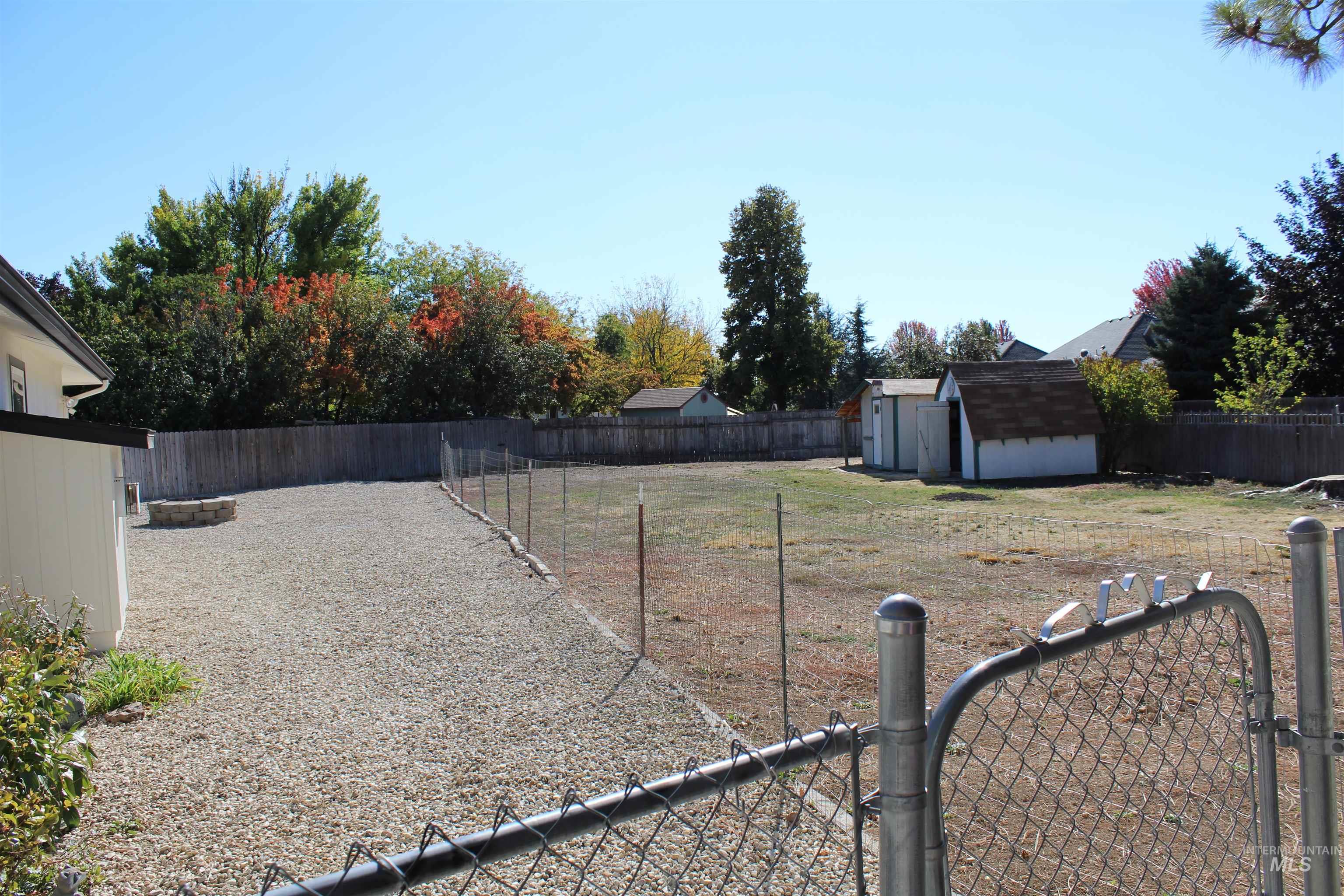 Fenced backyard featuring a shed and a gate