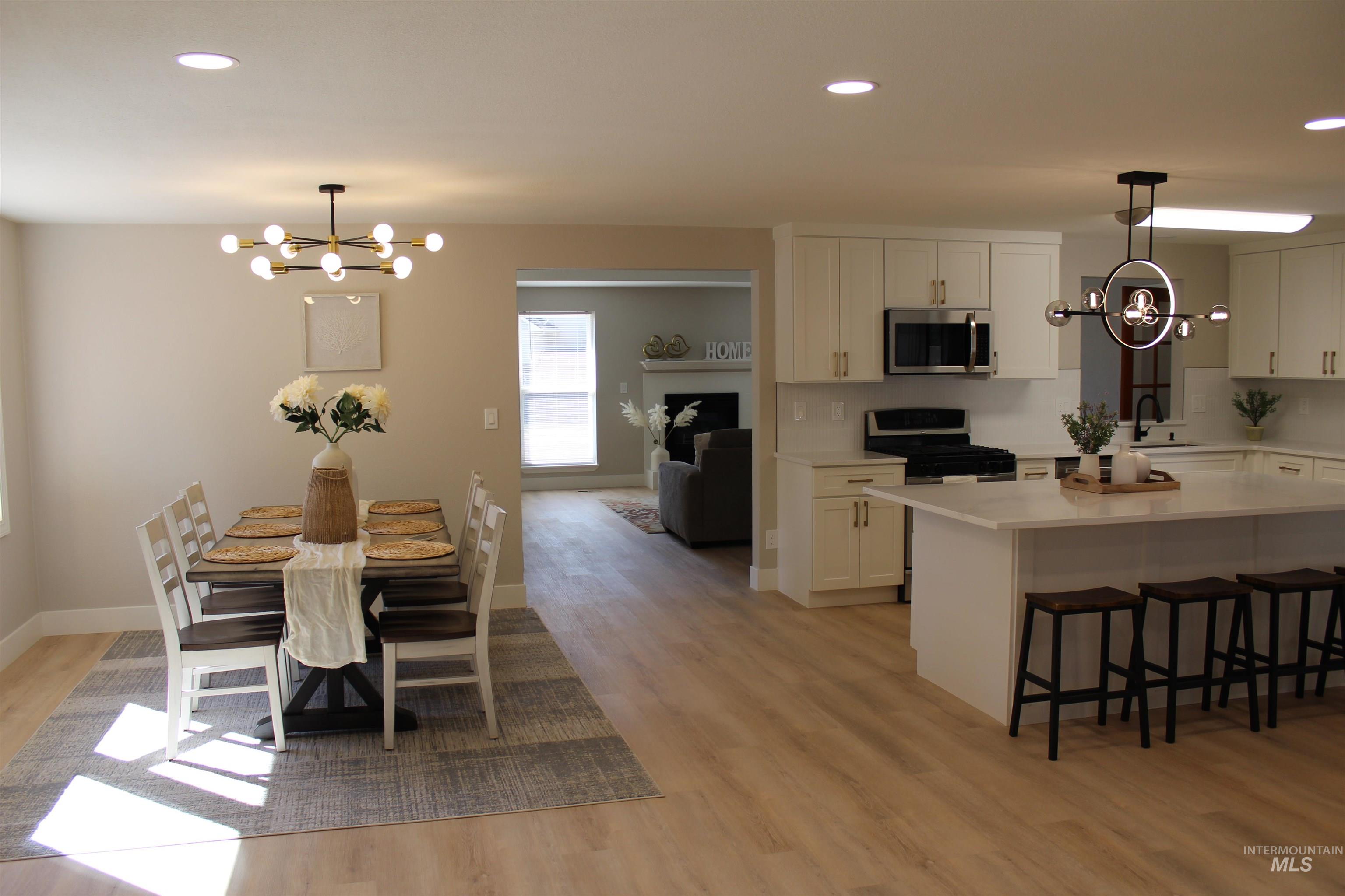 Kitchen featuring a chandelier, hanging light fixtures, recessed lighting, white cabinetry, and a breakfast bar area