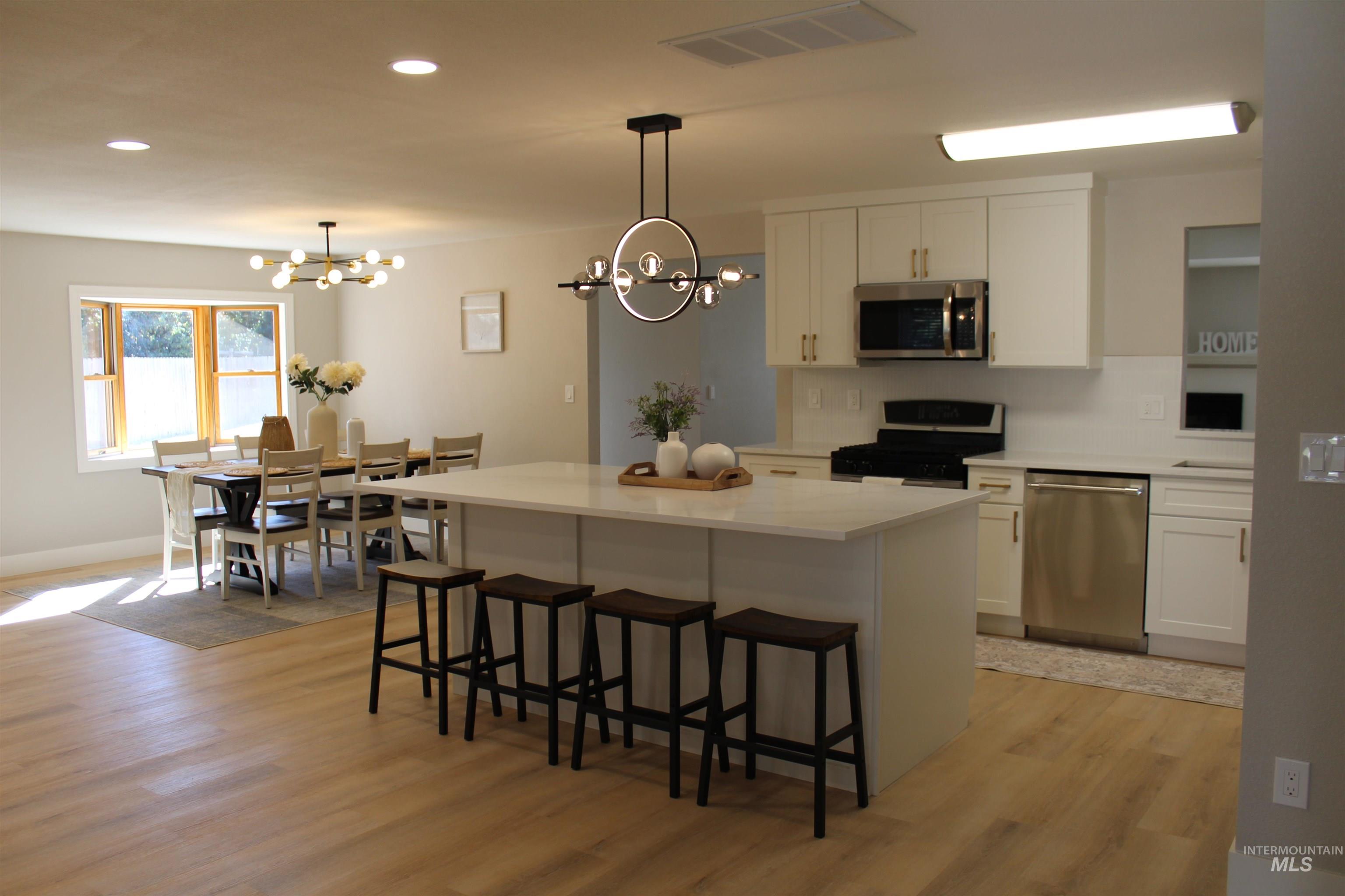 Kitchen with white cabinetry, a kitchen bar, recessed lighting, appliances with stainless steel finishes, and a kitchen island
