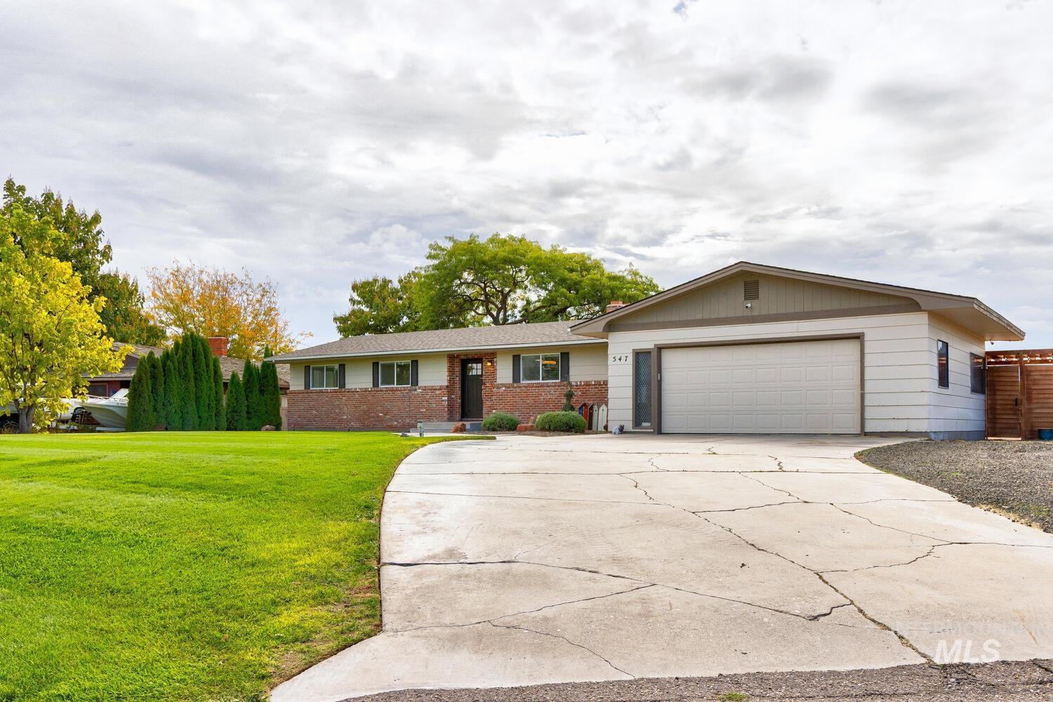 Ranch-style home featuring a front yard, concrete driveway, brick siding, and a garage